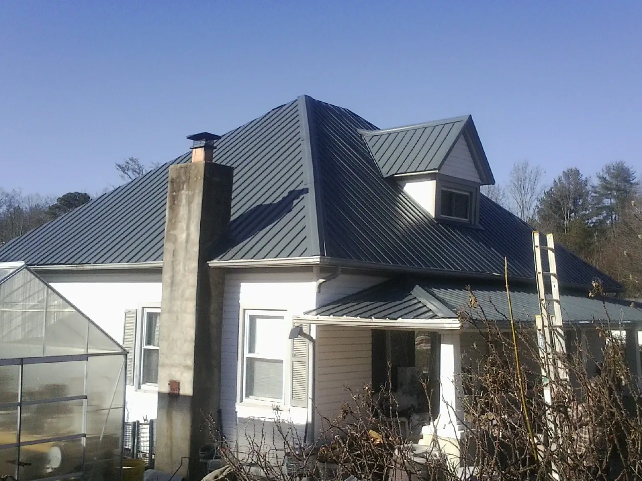 Dark blue standing seam metal roof on a white farmhouse with dormer — Slate & Tile Roof Repair by Roofing Brothers in Eastford