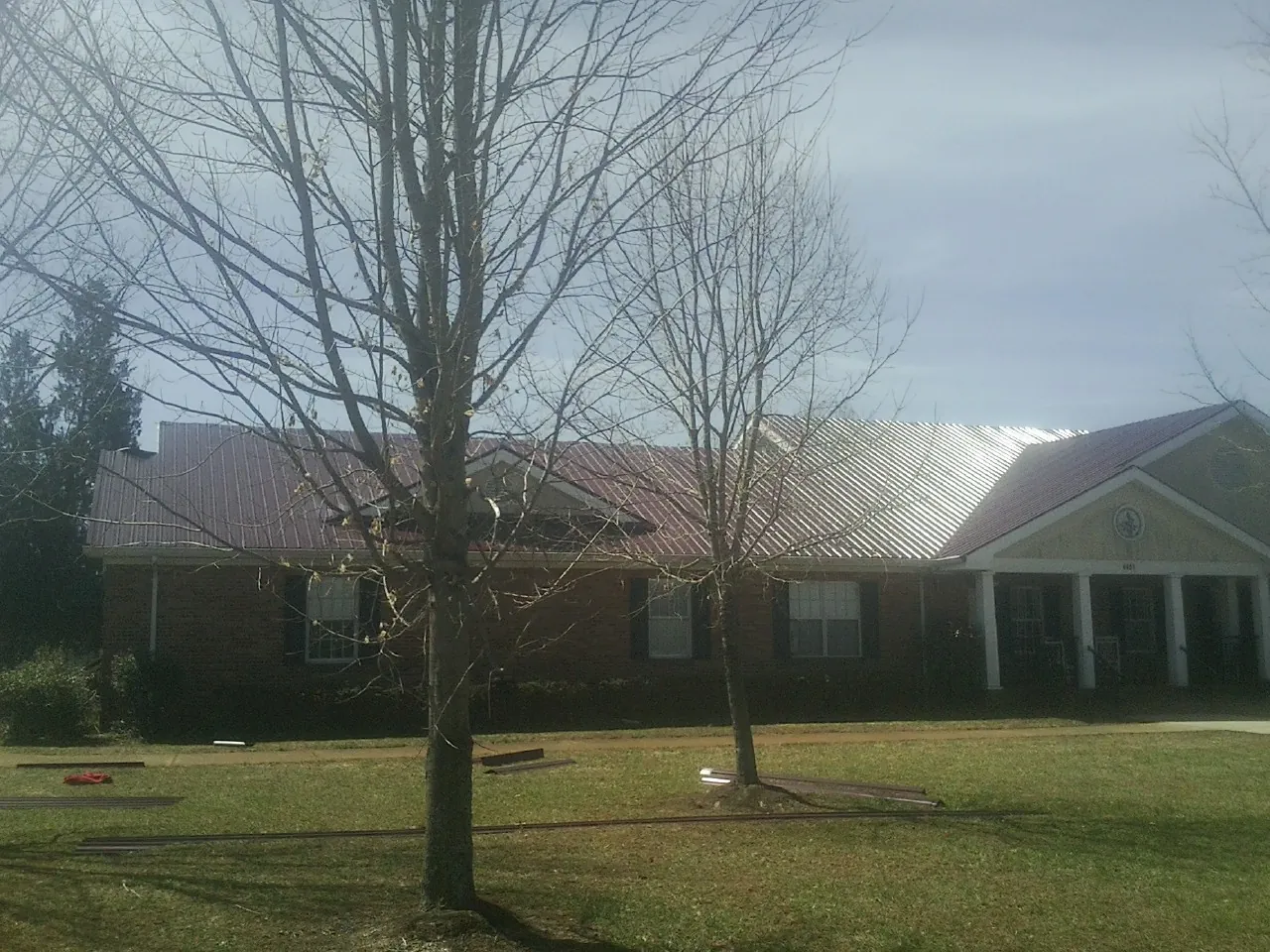 Red metal roof on a brick building seen from the front lawn in Eastford