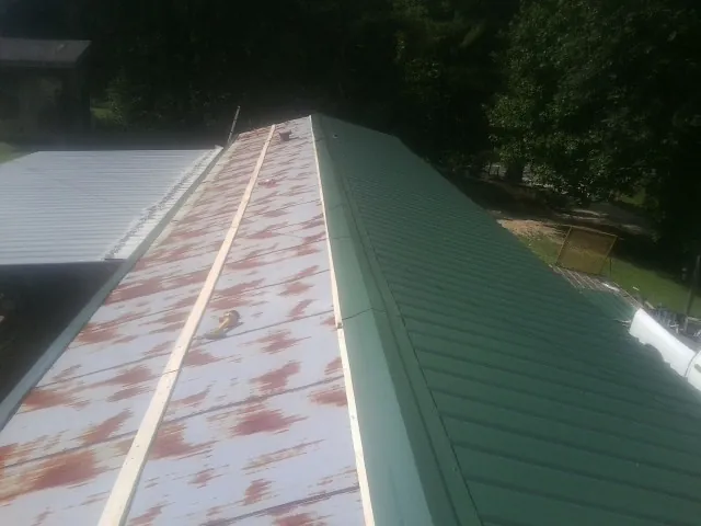 Old rusted panels beside newly installed green metal roofing — Wind Damage Roof Repair by Roofing Brothers in Eastford