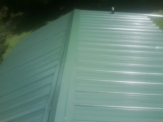 New green metal panels meeting at the ridge of a roof — Flat Roof Repair work by our crew in Eastford