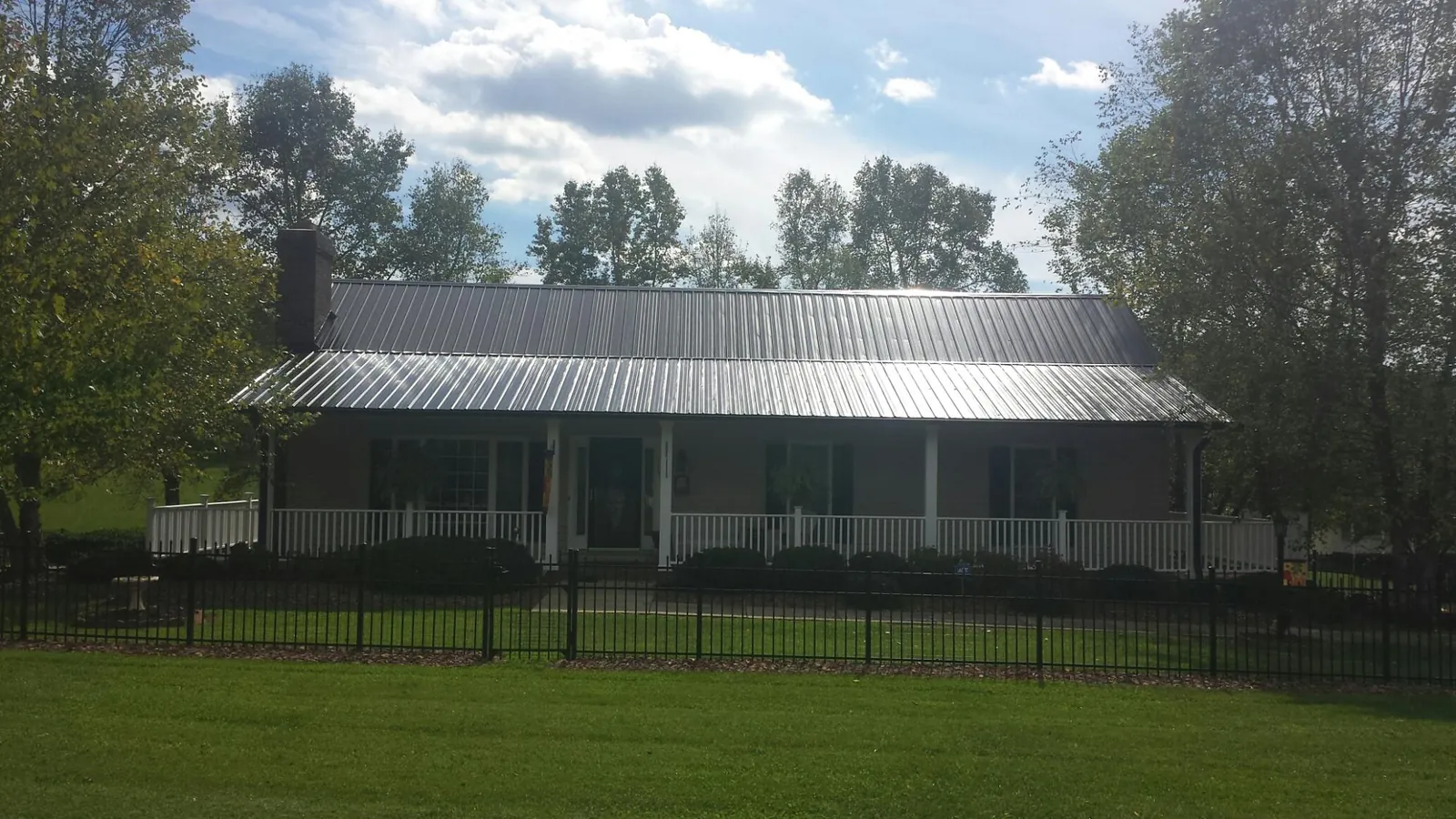 Gray metal roof on a brick ranch with a full width front porch — Gutter Guard Installation work by our crew in Eastford