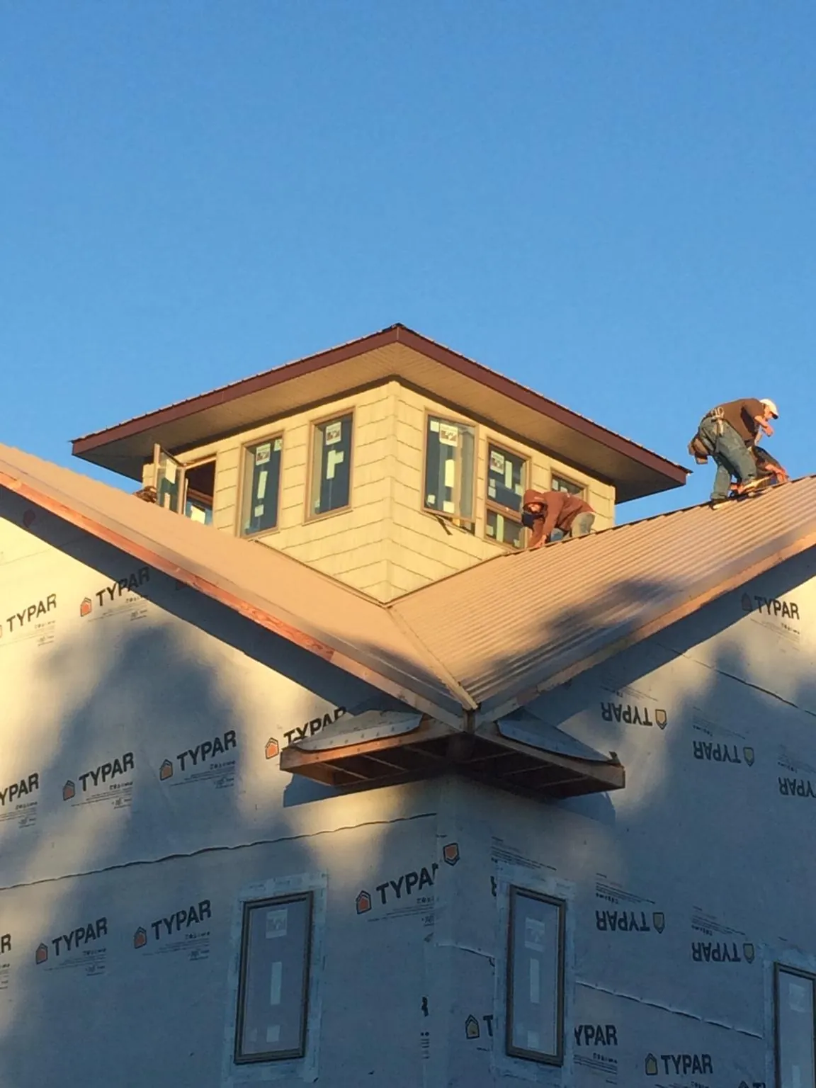Roofers working around a rooftop cupola on a new metal roof at sunset — Roof Waterproofing in Eastford by Roofing Brothers